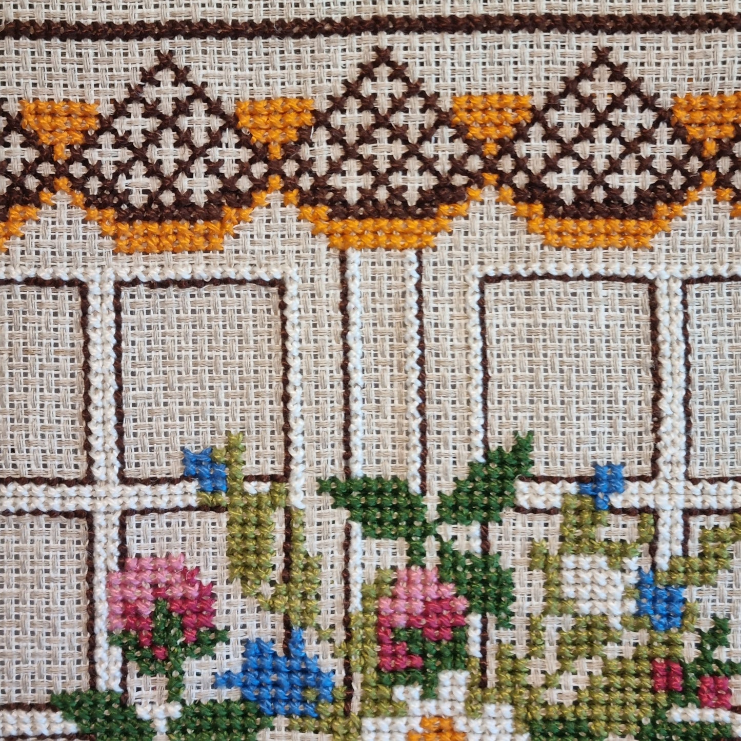 Close-up detail of diamond and chevron border pattern in brown and amber on linen ground