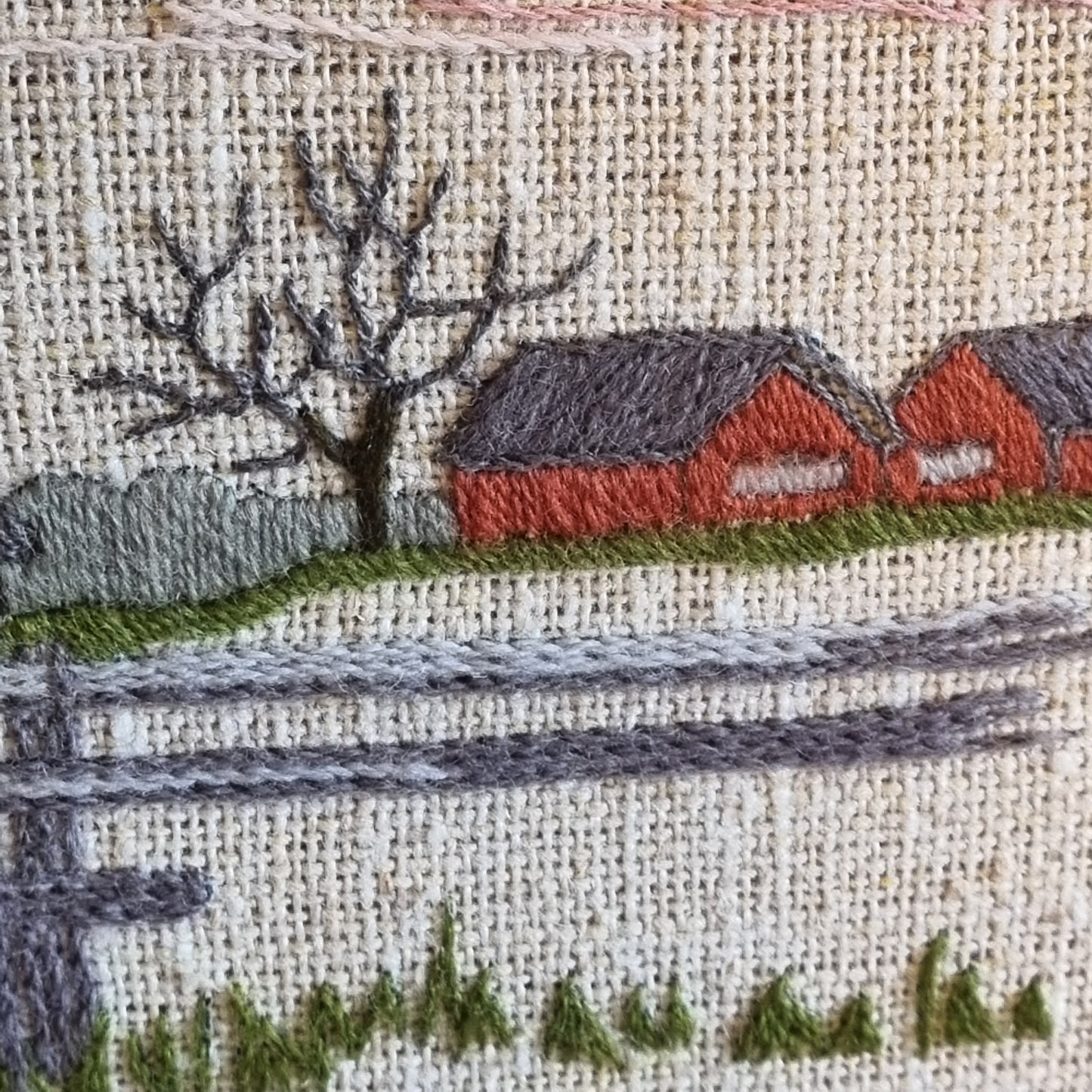 Close-up detail of red Falun barns and white farmhouse in Swedish winter landscape embroidery