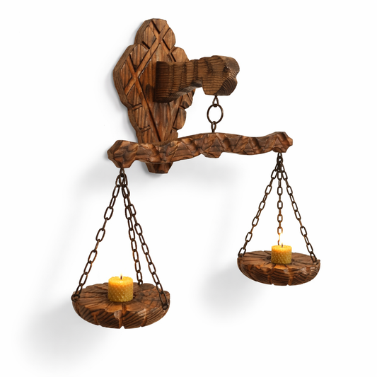 Rustic wooden wall scale candle holder with trays on chains holding lit candles, authentic vintage timeless charm