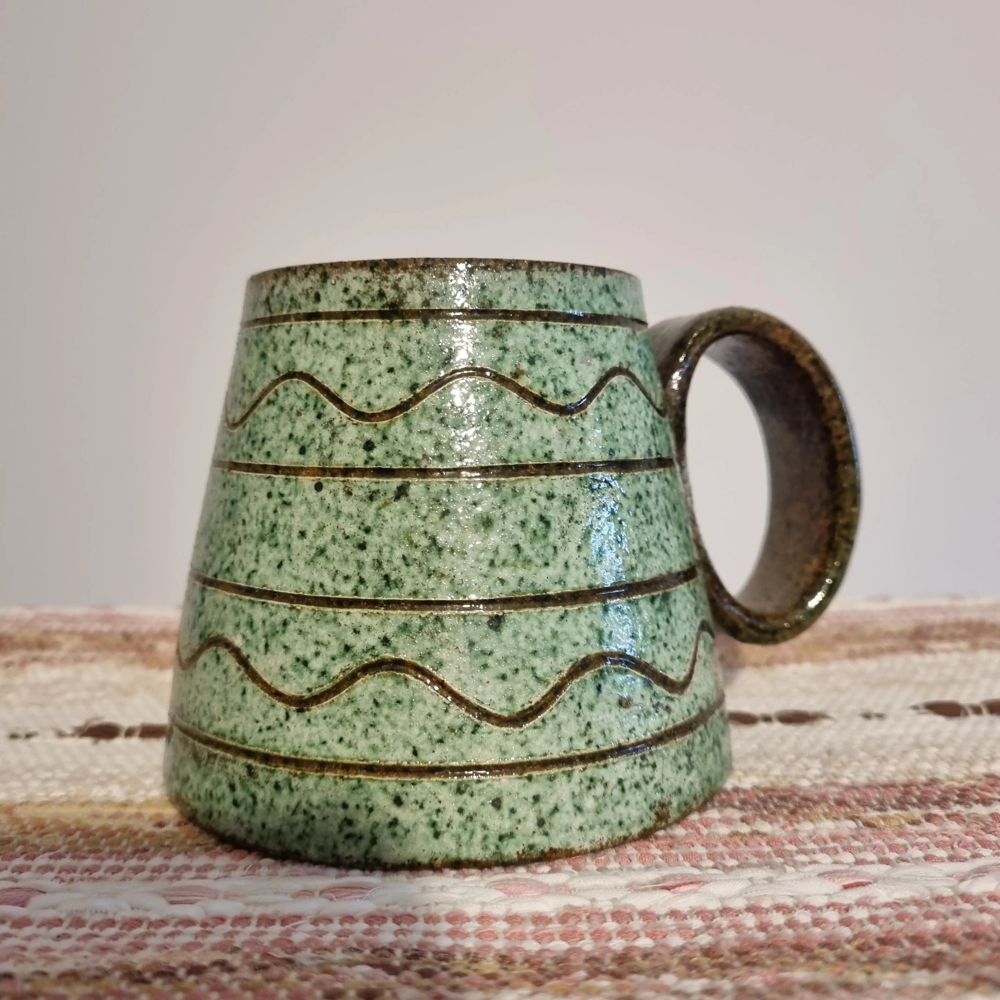 Krukmakeri Ystad Swedish Stoneware Mug – Speckled Green Glaze, Handmade with wavy brown lines on textured surface