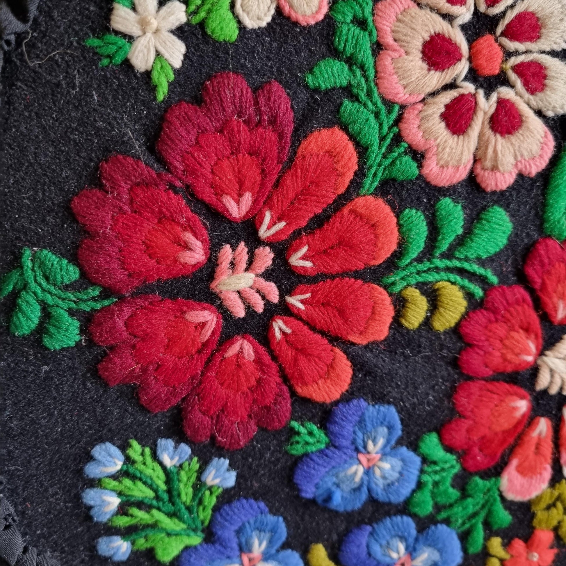 Vintage Embroidered Floral Throw Pillow: Black Ruffled Cushion with colorful detailed floral embroidery on black fabric surface