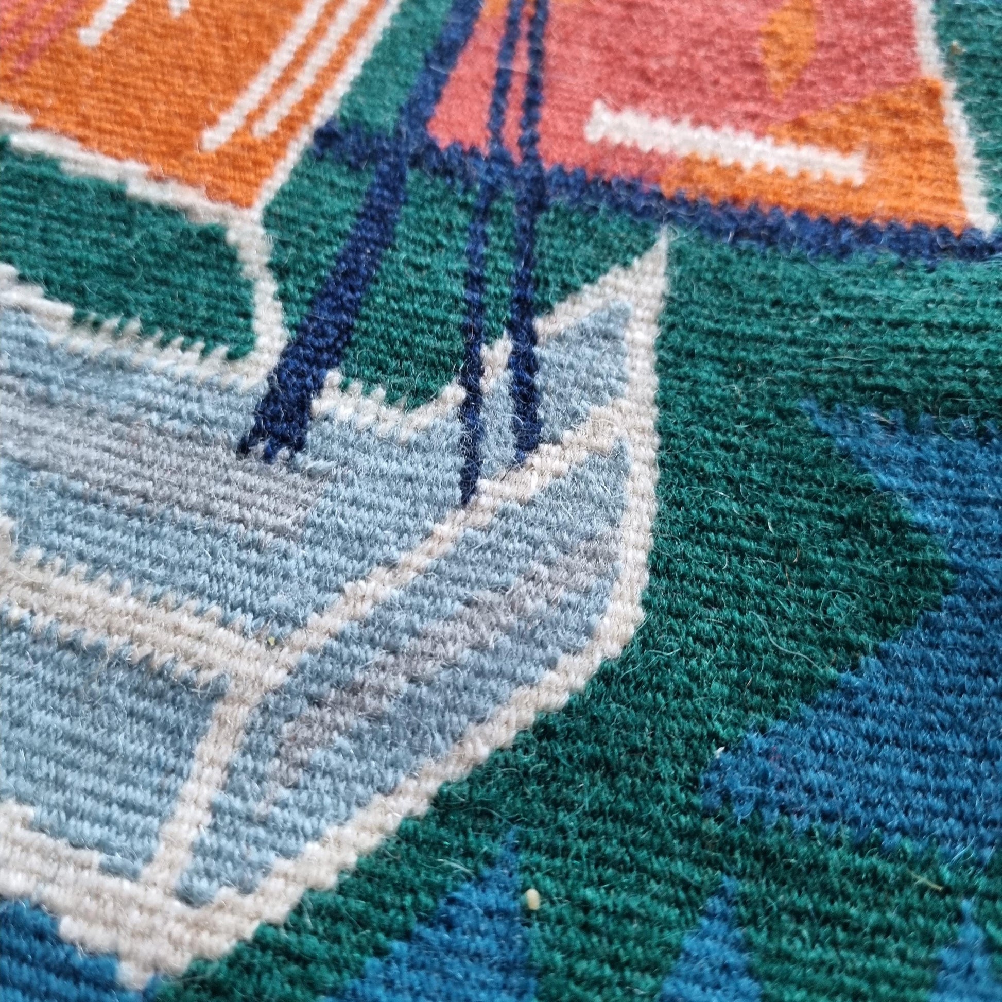 Close-up of textured woven fabric featuring boat design in blue, green, orange on Vintage Viking Ship Tapestry | 1970s Mid-Century Modern Woven Wall Art