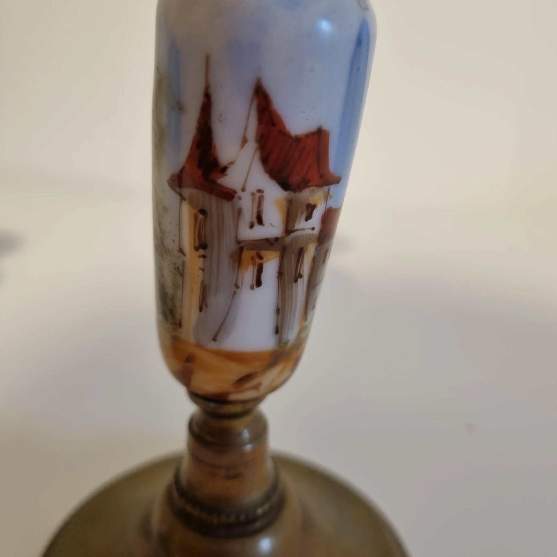 Vintage Brass Candle Holders: Hand-Painted European Village Scene, 1920s Pair with detailed rooftops on ceramic body.
