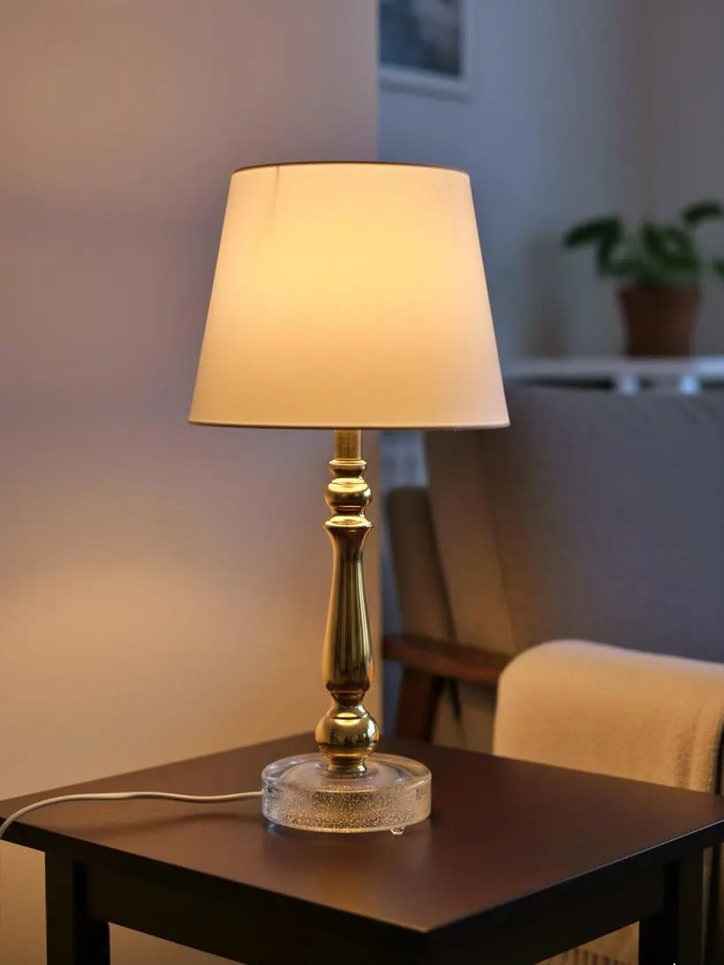 Elegant glowing Mid-Century Brass & Glass Table Lamp – Falkenbergs Belysning, Swedish Modern Design on dark side table.